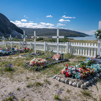 Gravesites decorated with artificial flowers and white crosses