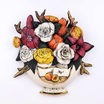 Porcelain sculpture of an illustrated vase holding colorful flowers.