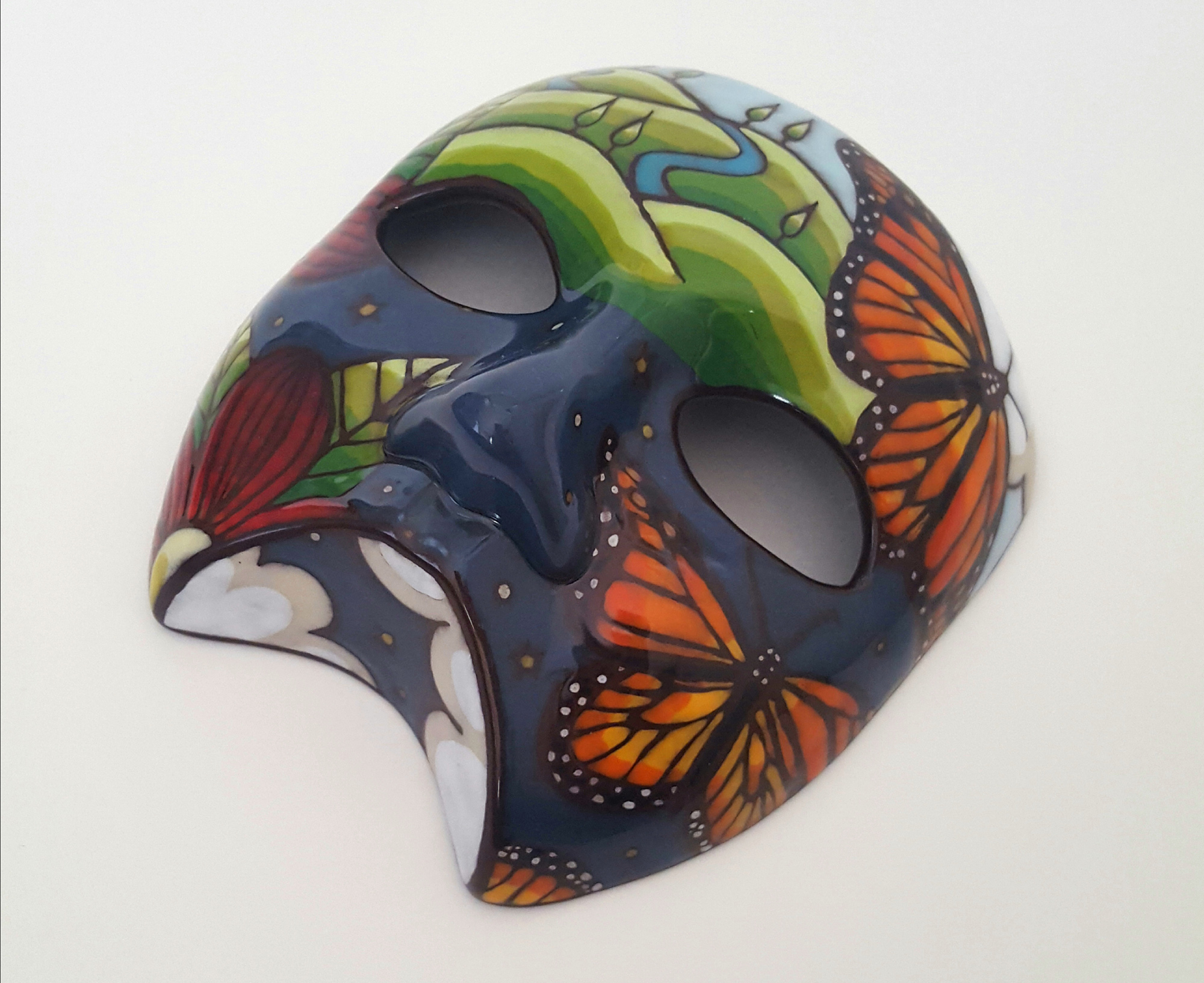 Mask with painted images of monarch butterflies, clouds, red flowers, and landscapes