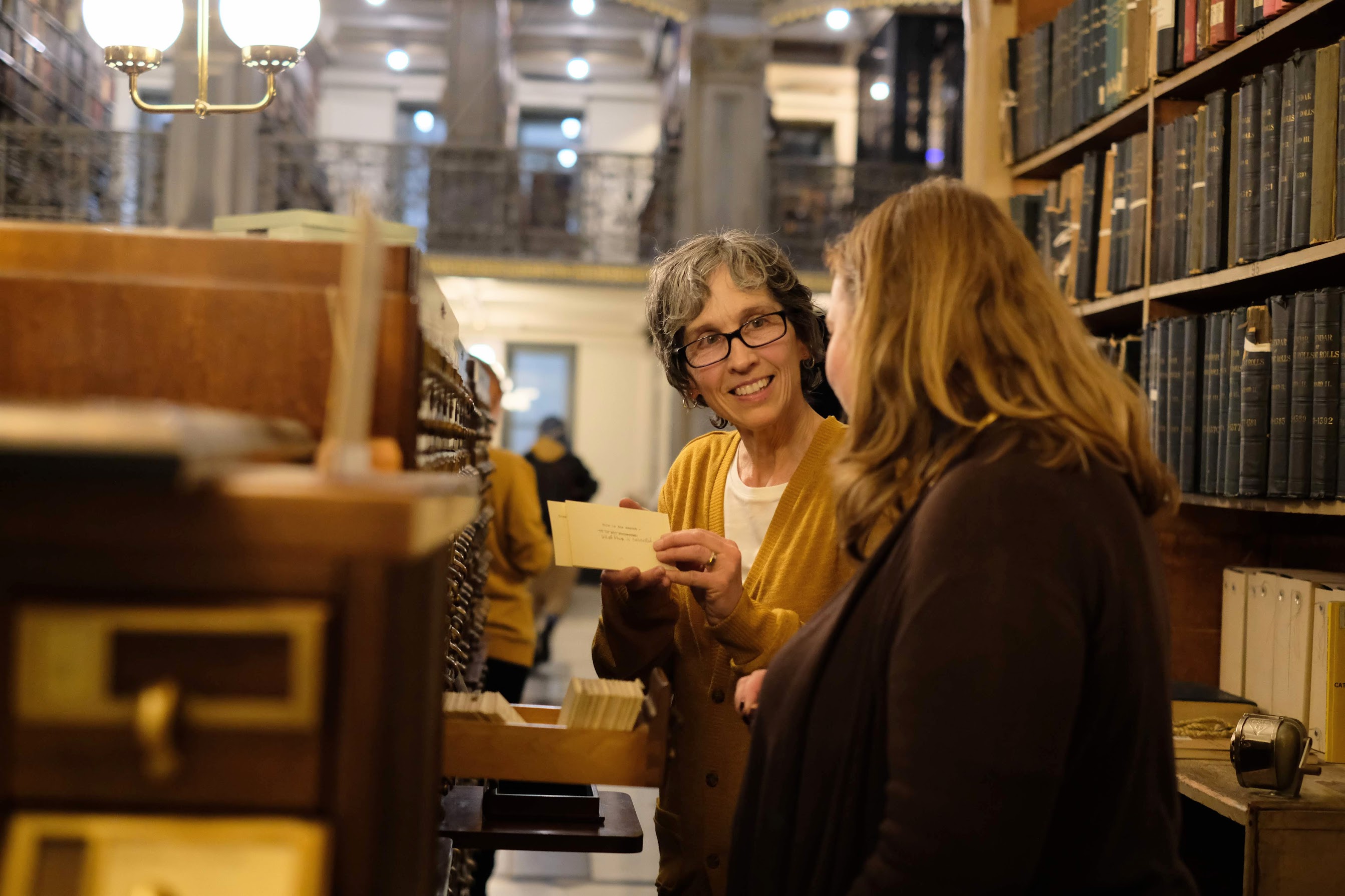 performer Ursula Marcum and audience member at the card catalog in "See Also"