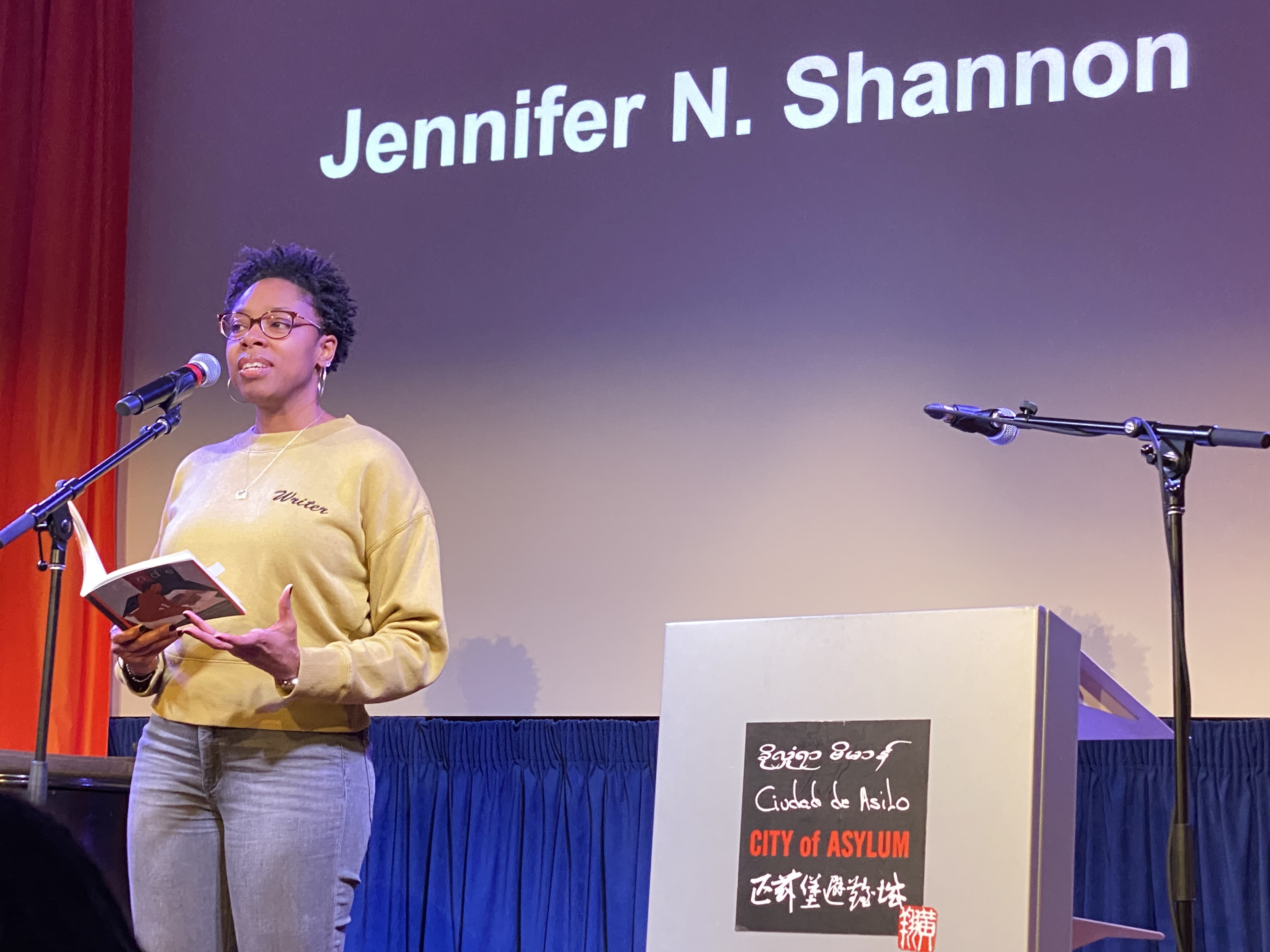 a photograph of Jennifer N. Shannon on stage, reading at City of Asylum in Pittsburgh, PA.