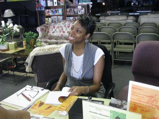 Jennifer N. Shannon smiling while sitting with a book ready to sign