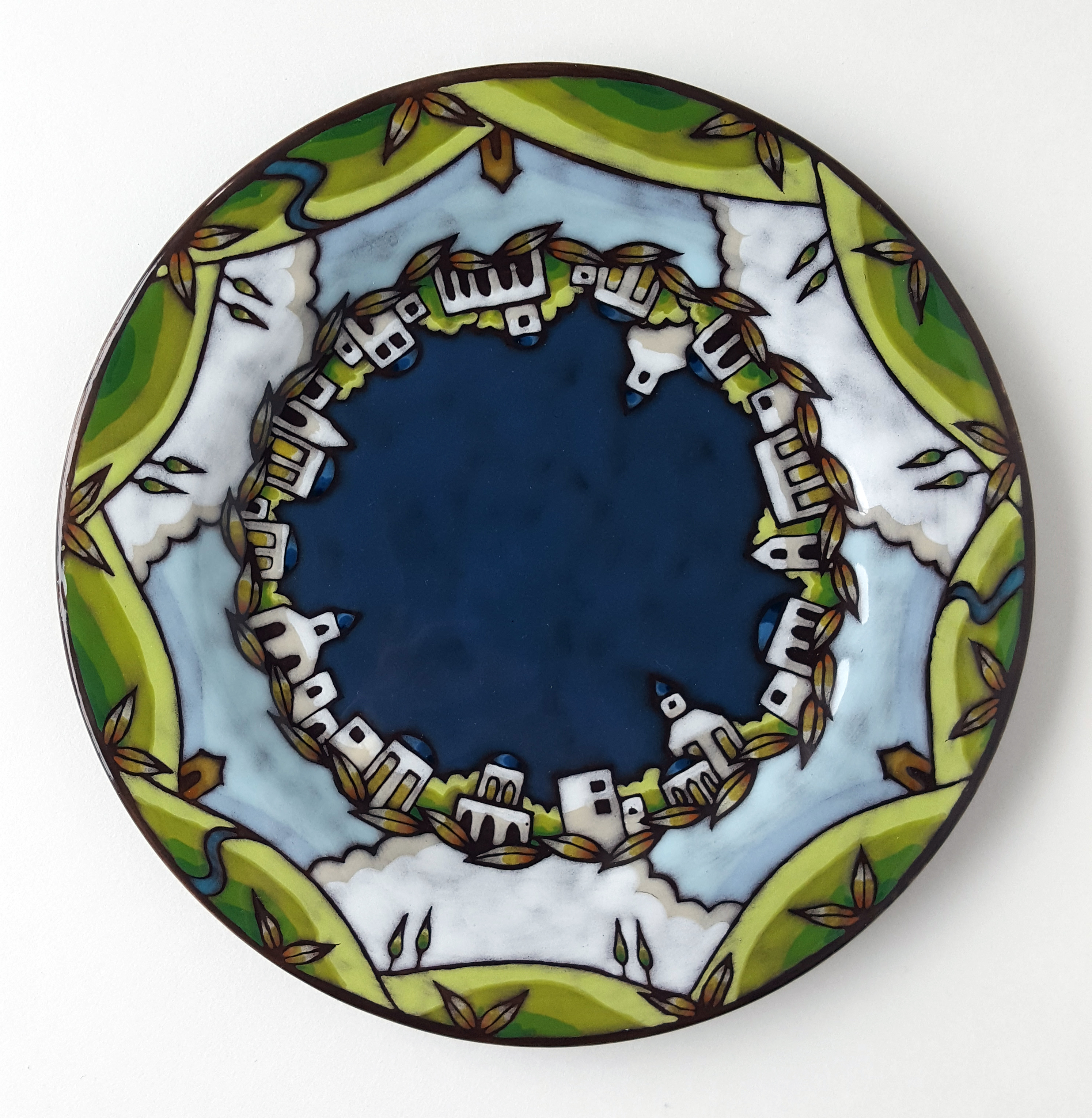 Plate with images of white buildings, leaves, and hills in a circle