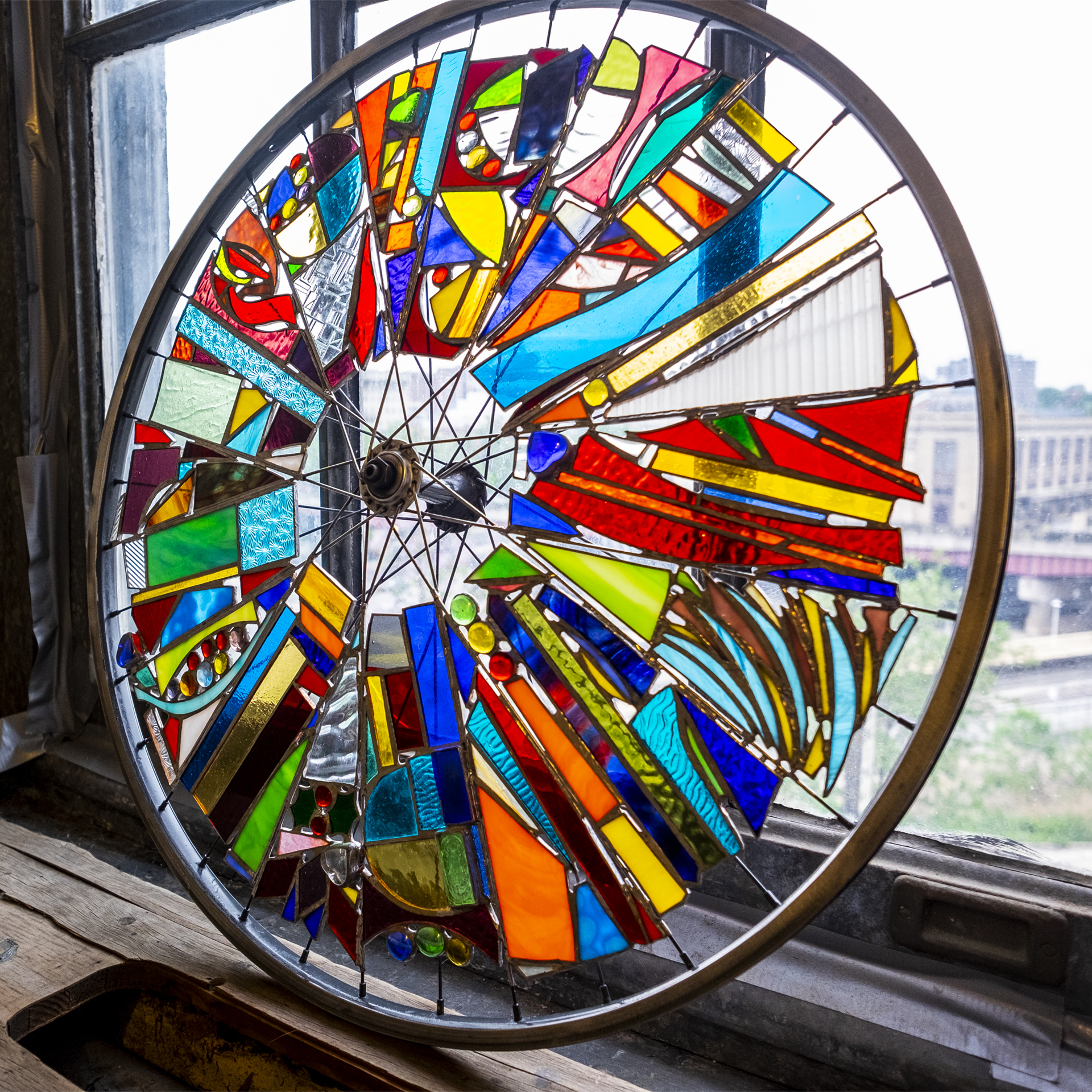 Bicycle wheel art with colored glass inserted between spokes