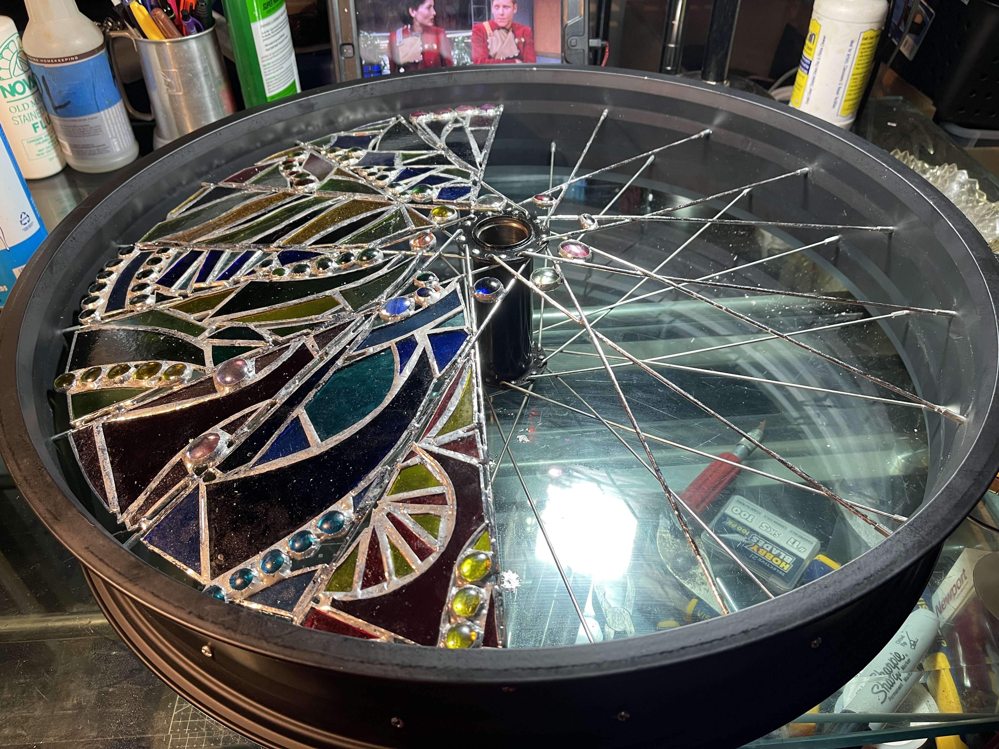 Stained glass panels in process of being inserted between bicycle wheel spokes