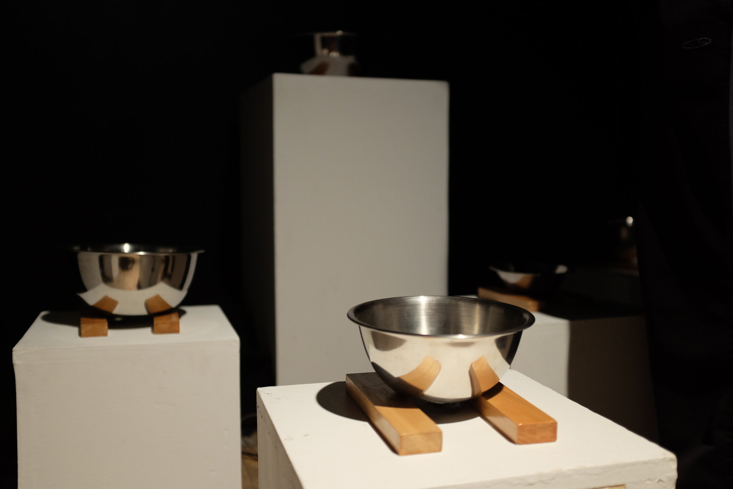 three steel bowls on plinths in a gallery