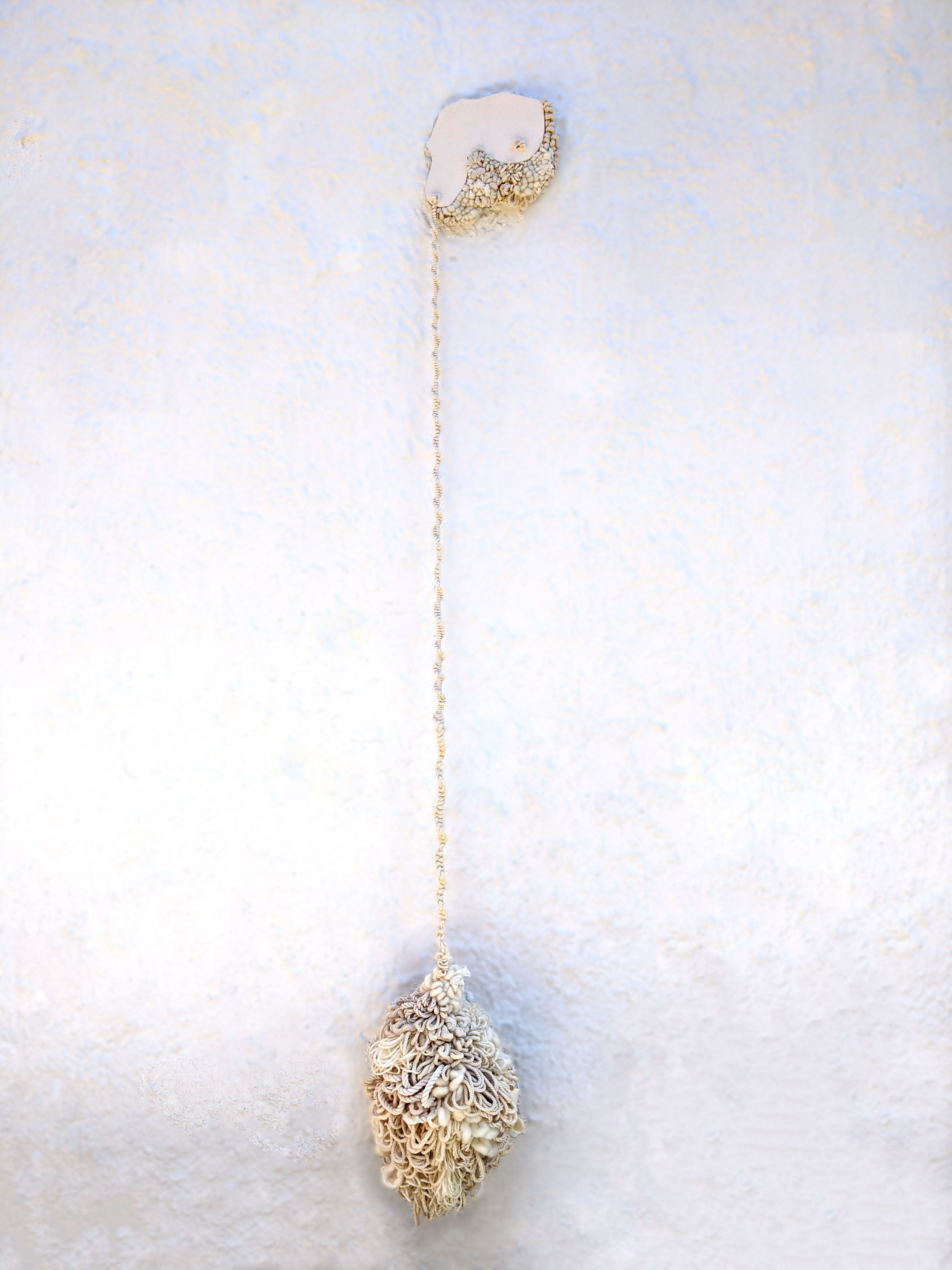 Fiber wall hanging, ball of fiber hanging from ceramic breast