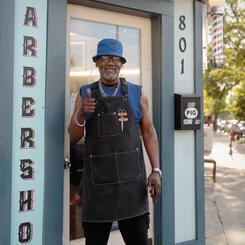 A man poses for a portrait outside his barbershop in Pigtown.