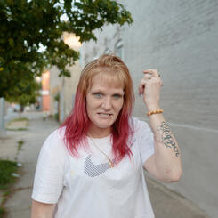 A woman poses for a portrait and shows off her newly dyed pink hair in Pigtown.