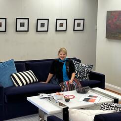 Gallery Shot: Monument Sotheby's- Solo exhibition Tracy seated with miniature Imagine Series paintings in background 