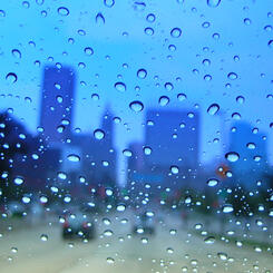 downtown through a wet blue car window