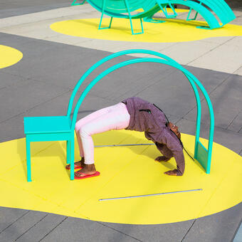 Yoga Chair. A girl does a backbend below a sculptural chair, part of The Chairs, a sculptural seating public art installation in Washington DC.