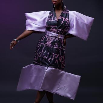 Model wearing Afrofuturistic fashion piece made by Yele fashion designer based in Baltimore. The dress is made with African print fabric (power of love print curated by Yele). The sleeves of the dress is very wide and also has wide bottoms which encourages an air of taking uo your own space!