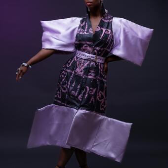 Model wearing Afrofuturistic fashion piece made by Yele fashion designer based in Baltimore. The dress is made with African print fabric (power of love print curated by Yele). The sleeves of the dress is very wide and also has wide bottoms which encourages an air of taking uo your own space!