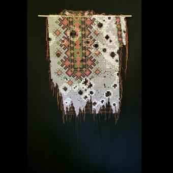 Julianna Dail's paper tapestry made from circles cut from security envelopes and circa 2022 Ukrainian magazines. The piece looks like a tethered, torn, and worn out Ukrainian traditional blouse.