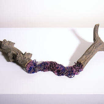 wooden stick cut in half and joined with purple and blue strings of glass beads