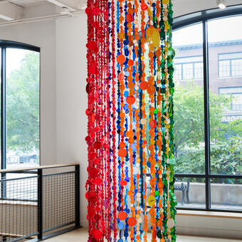 Plastic bottle caps hanging from ceiling from a hoop.