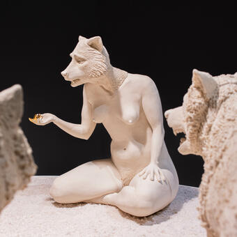 porcelain wolf headed human figure, surrounded by porcelain wolves. 