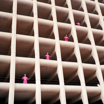 Band Powerwasher all wearing pink jumpsuits standing by the openings in a parking garage photographed from below.