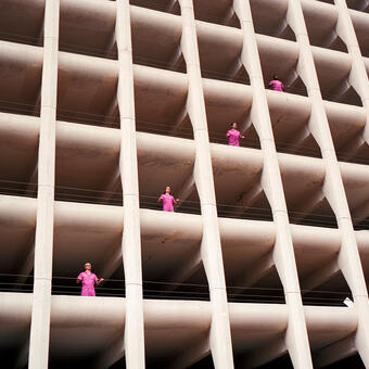 Band Powerwasher all wearing pink jumpsuits standing by the openings in a parking garage photographed from below.
