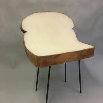 4" thick foam cut and painted to resemble a large slice of white bread gently contoured to form the seat of a chair which is mounted on 4 steel rod legs giving it a contemporary look.