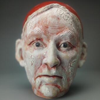 Portrait head sculpture if a man wearing a red cap made of clay and glaze
