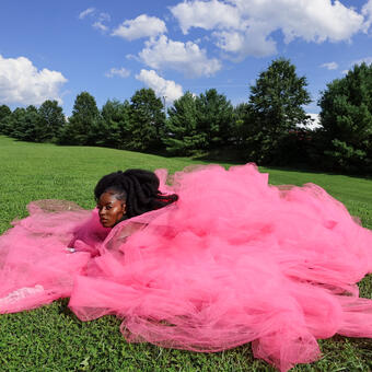 woman in pink dress laying in field