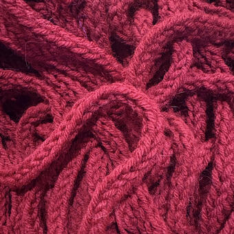 A large mass of thick red yarn is tangled on the floor.