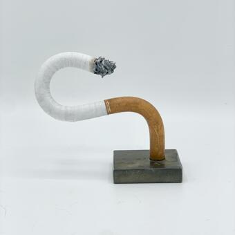 A sculpture of a cigarette made of steel and bent into an S curve