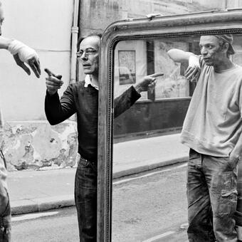 man holding a mirror pointing at a man with a bandaged hand lifting his arm