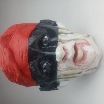 A sculpture of a young man's head, painted in color blocks of red,  black and white