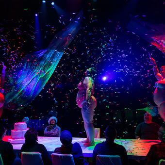 Three fat actors stand on a table and get rained on with confetti!