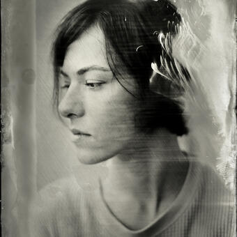 A wet plate collodion portrait of a woman in profile; there is collodion silver artifact on the image, creating fire-like shape