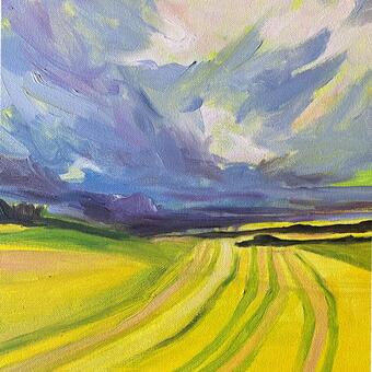 Greenish yellow tilled fields curve to the horizon under purplish blue clouds.