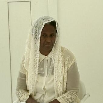 A photo of Pamela Woolford seated and dressed in old-timey off-white lace garb and emoting as she performs as Harriet Tubman