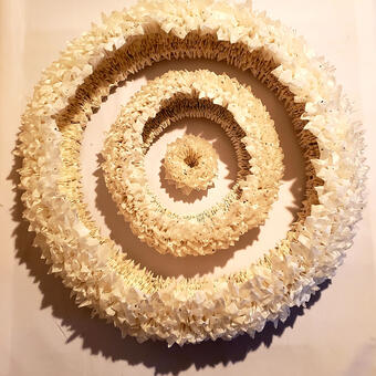 "An intricate paper art piece featuring a single seed sprouting into a lush tree full of fruit, symbolizing the growth of hope and the abundance it brings to life. The artwork is meticulously crafted using layers of paper to create depth and detail."