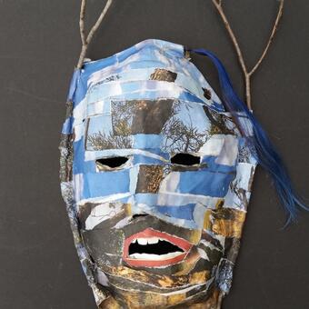 Paper mâché mask with images of sky and tree branches at top and logs, branches and roots at bottom. The lips are parted with teeth showing, representing an entity trying to breathe.  A blue hair-extension was added at top and a black to brown "fade" added at bottom. Real twigs run along the side and extend from the top of the mask. 