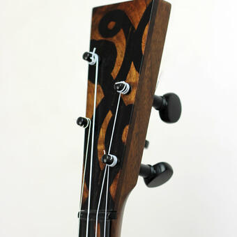 A detail shot of the banjo's peghead from a three-quarter view, with the walnut/ ebony overlay visible