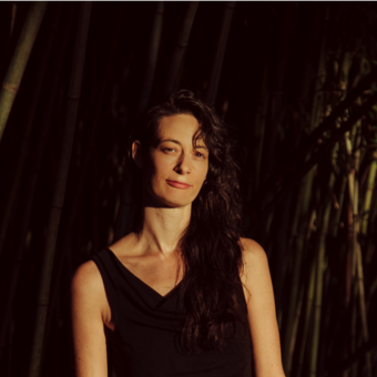 Lola B. Pierson looking at camera with hair swept to one side in black tank top.