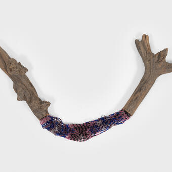a stick cut in half and mended with strings of purple and pink beads