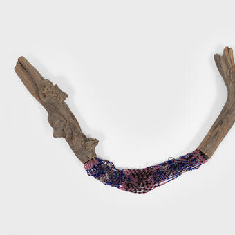 a stick cut in half and mended with strings of purple and pink beads