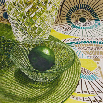 Green lime in a crystal bowl atop a green mat all sitting on a decorated fabric with Asian umbrella motifs.