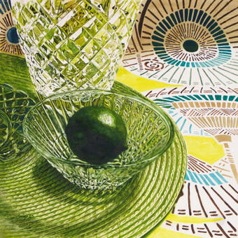 Green lime in a crystal bowl atop a green mat all sitting on a decorated fabric with Asian umbrella motifs.