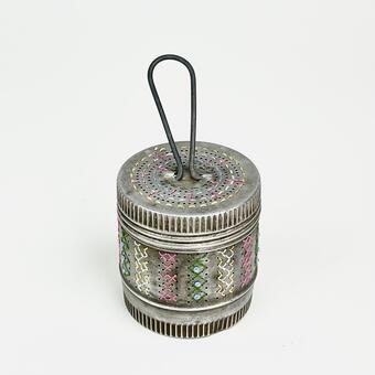 Embroidered patterns within a vintage tea infuser using blue, pink, yellow and green linen thread.