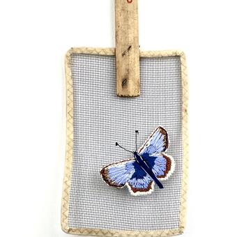 Embroidered butterfly image using blues, ivory and brown embroidery thread on a vintage fly swatter.