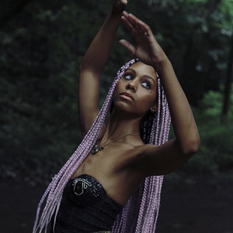 photo of a woman with purple hair, leaning back with her arms up
