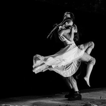 Image of violent fight choreography, a small white woman lifted by a larger man. Black and white, dance like