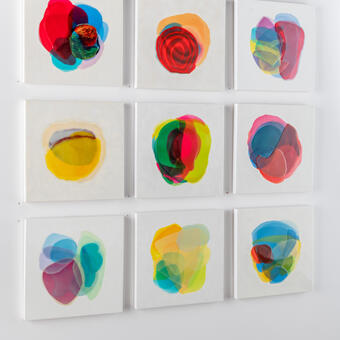 Wall of nine paintings each with colorful abstract forms on white backgrounds by Farida Hughes
