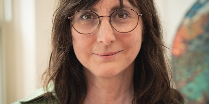 1:58 AMClaude responded: Woman with shoulder-length brown hair and wire-frame glasses, wearing a green linen shirt and a beaded necklace, photographed in front of an abstract artwork.Woman with shoulder-length brown hair and wire-frame glasses, wearing a green linen shirt and a beaded necklace, photographed in front of an abstract artwork.