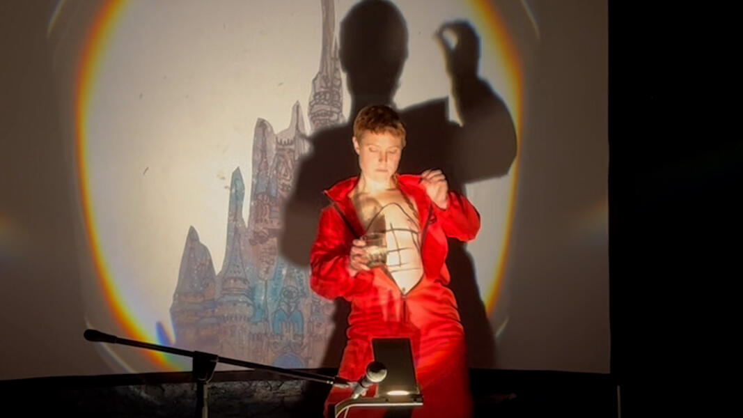 Red draws on their bare chest while performing in a projection of a castle.